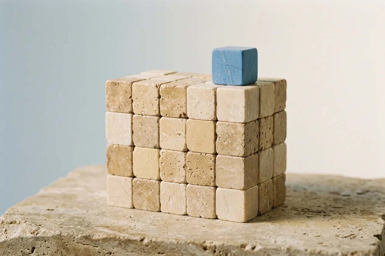 Block aus vielen Travertinwürfeln, oben drauf der blaue Würfel