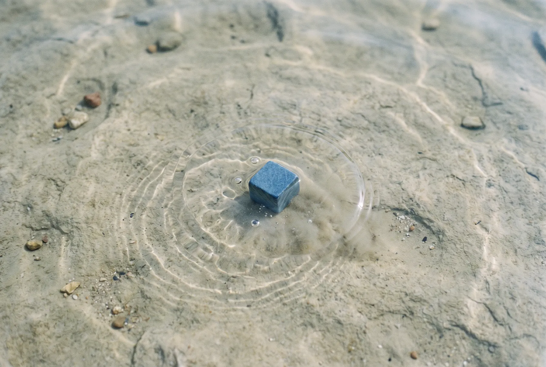 Blauer Würfel über hellem Sand
